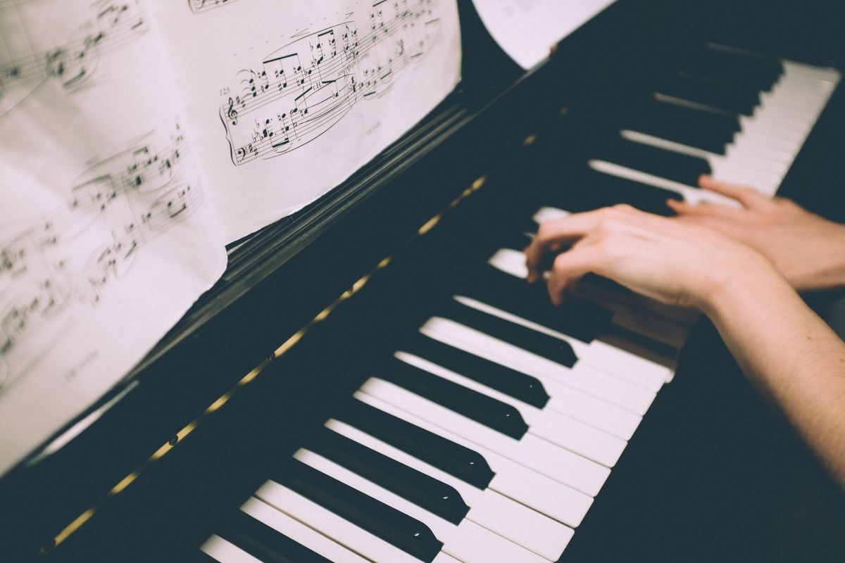 Mains au piano, partition ouverte sur le pupitre